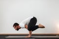 Athletic young man does handstand and keeps balance. Professional guy is doing yoga in the gym