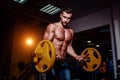 Athletic young man doing exercises with barbell in gym. Handsome muscular bodybuilder guy is working out. Royalty Free Stock Photo