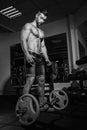 Athletic young man doing exercises with barbell in gym. Handsome muscular bodybuilder guy is working out. Monochrome image. Royalty Free Stock Photo