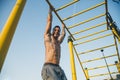 Athletic young man hanging from the bars at the calisthenics gym outdoors