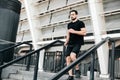 Athletic young man running down from stairs. Urban sport concept. Apartment block on background. Active living. Outdoor Royalty Free Stock Photo