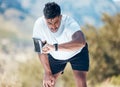 Athletic young mixed race man looking at his watch while exercising outdoors. Handsome indian looking serious while Royalty Free Stock Photo