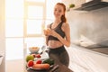 Athletic young red haired woman in the kitchen with a glass of fruit centrifuged juice