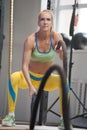 Athletic Young Woman Battling ropes during workout at the gym