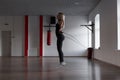 Athletic young woman in black sportswear jumps on a skipping rope and burns calories in a fitness studio. Girl in training