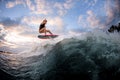 Athletic young woman in swimsuit jumping up on surf style wakeboard against blue cloudy sky Royalty Free Stock Photo