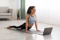 Athletic young woman doing yoga in living room, using laptop Royalty Free Stock Photo