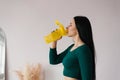 Athletic young woman drinks water from a yellow bottle after a workout at home Royalty Free Stock Photo