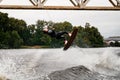 athletic young woman holds rope and extreme jumping over the splashing wave on wakeboard