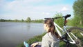 Young woman riding a bike through the park on the background of a lake or river.