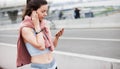 Athletic young woman in sports uniform installs music, checks the fitness application on smartphone, catches a network.