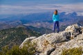 Athletic young woman standing on the rocky top of the mountain against the blue sky Royalty Free Stock Photo