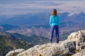 Athletic young woman standing on the rocky top of the mountain against the blue sky Royalty Free Stock Photo