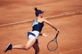 Athletic young woman, tennis player in motion, hitting ball with racket. Female player training at open air tennis court Royalty Free Stock Photo