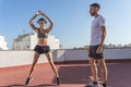 Athletic young woman doing the jumping jack exercise while being supervised by her personal trainer Royalty Free Stock Photo