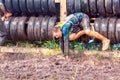 athletic youth participates in a race of heroes and overcomes obstacles car tires on a summer day in the village of Roshchinsky . Royalty Free Stock Photo