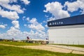 Landscape view of a Delta building and planes with blue sky and clouds
