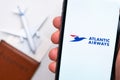 Atlantic Airways airline. A mobile phone and Atlantic Airways airline application in mans hand. There is a passport and