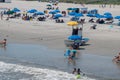 Atlantic City, New Jersey beach showing people on beach chairs sunbathing, many blue umbrellas and a lifeguard stand and boat Royalty Free Stock Photo