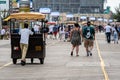ATLANTIC CITY, NEW JERSEY - JUNE 18, 2019: A pedicab pushes his customers past the Boardwalk lined with restaurants, shop and