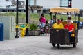 ATLANTIC CITY, NEW JERSEY - JUNE 18, 2019: A pedicab pushes his customers past the Boardwalk lined with restaurants, shop and