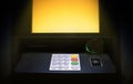ATM - automated teller machine cash machine and screen with yellow light in the shadow