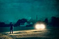 An atmospheric moody edit of a man standing in front of car headlights in a field at night. With a grunge, texture edit