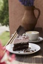 Atmosperic natural piece of cake and a glass of cappuccino on wooden table outdoor in the cafe terrace. Aesthetic coffee