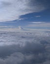 Atmosphere beautiful blue sky with clouds view from an airplane window. A plane is flying above the clouds