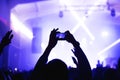 Atmosphere of a cool music festival with a stage floodlit with hands from the crowd with a smartphone