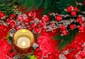 An atmosphere of festiveness is created at Christmas by red berries and burning candle.