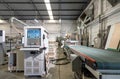 Atmosphere inside wooden furniture factory with piles of plywood and modern machinery, controlled by computer system