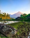 The atmosphere of small village in Indonesia in the morning with a beautiful view of a mountain and green rice field Royalty Free Stock Photo