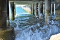 the atmosphere under the pier with the waves crashing and the bridge poles lined up