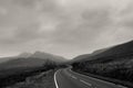 An atmospheric black and white edit of a road heading towards mountains on a stormy winters day. Snowdonia, Wales. UK.