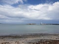 Atmospheric clouds at the beach with Donaghadee lighthouse on the horizon Royalty Free Stock Photo