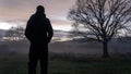 An atmospheric concept. Of a lonely figure, back to camera. standing in the countryside, looking at the sunset. On a cold, misty, Royalty Free Stock Photo