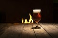 Atmospheric evening in a pub. Beer glass on a dark wooden background with fire place