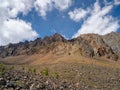 Atmospheric landscape with rocky mountain wall with pointy top in sunny light. Loose stone mountain slope in the foreground. Sharp Royalty Free Stock Photo