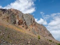 Atmospheric landscape with rocky mountain wall with pointy top in sunny light. Loose stone mountain slope in the foreground. Sharp Royalty Free Stock Photo