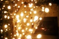 Atmospheric magical christmas eve at fireplace. Stylish christmas illuminated tree on background of golden lights bokeh and