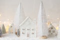 Atmospheric miniature white christmas village. Stylish little christmas houses and trees on snow blanket with glowing lights. Royalty Free Stock Photo