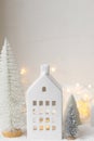 Atmospheric miniature white christmas village. Stylish little christmas houses and trees on snow blanket with glowing lights. Royalty Free Stock Photo