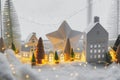 Atmospheric miniature winter village. Stylish little ceramic houses and christmas wooden trees on snow blanket with glowing lights Royalty Free Stock Photo