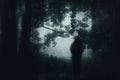 An atmospheric, moody concept. Of a ghostly figure standing on a forest path on a foggy day. With a grunge, textured edit