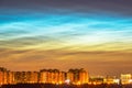Atmospheric phenomenon glowing of noctilucent clouds. Night sky and spectacular silvery clouds, silhouettes of city buildings