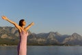 Atmospheric photo. A beautiful young woman is standing with her arms outstretched in a summer sarafan. Mediterranean Sea and high Royalty Free Stock Photo