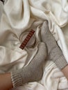 Atmospheric photo. The girl`s feet are in wool socks with a mug of cocoa and milk chocolate Royalty Free Stock Photo