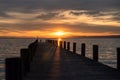 Atmospheric photo of the sunset at Lake Neusiedl with a wooden pier in the foreground. The wooden poles cast a shadow on the jetty Royalty Free Stock Photo