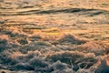 Atmospheric sea foam at colorful sunset, breathtaking scene of deep sea waves in gold water sparkles